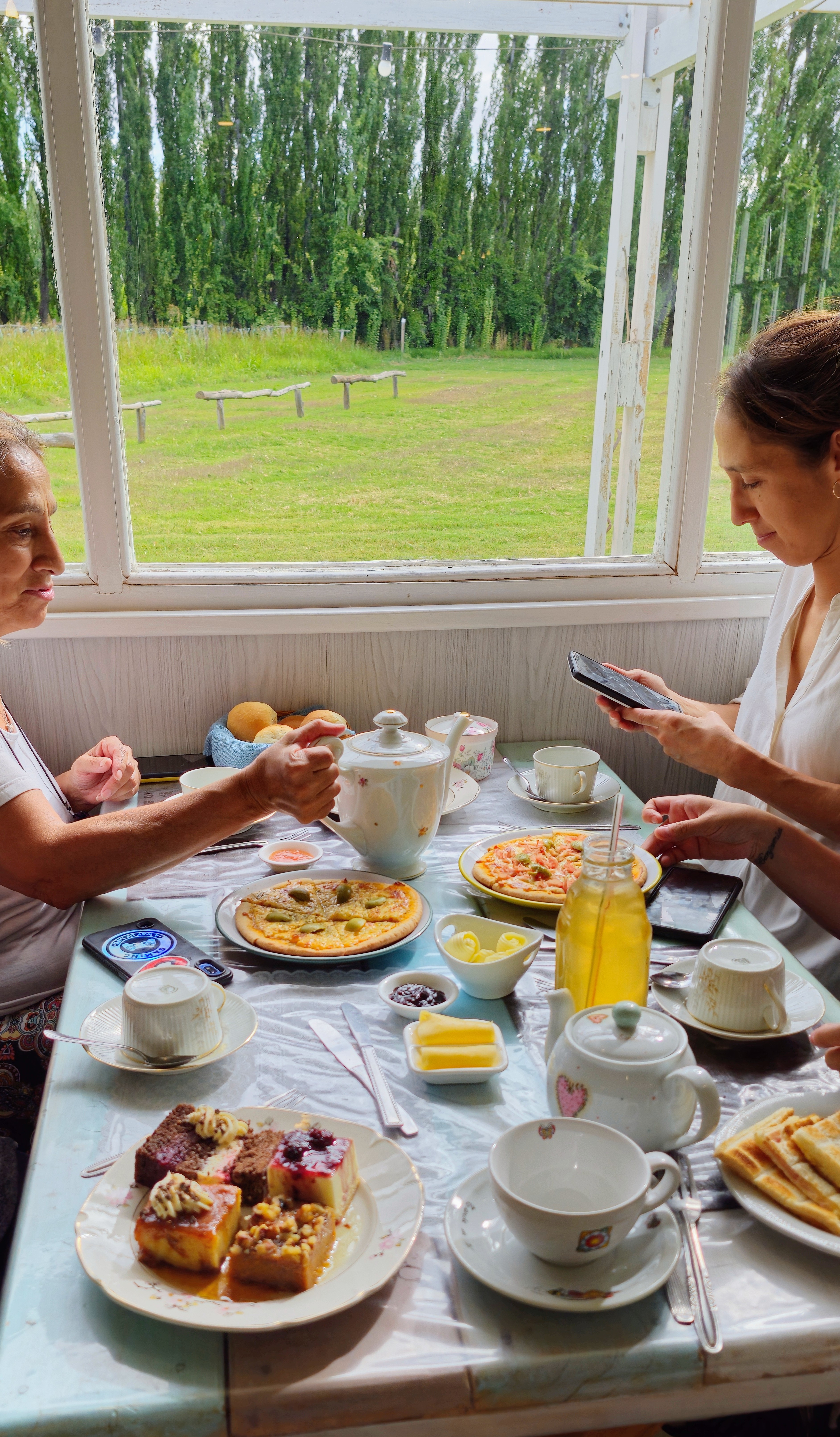 2 mujeres sentadas en una mesa disfrutando una merienda salada y dulce