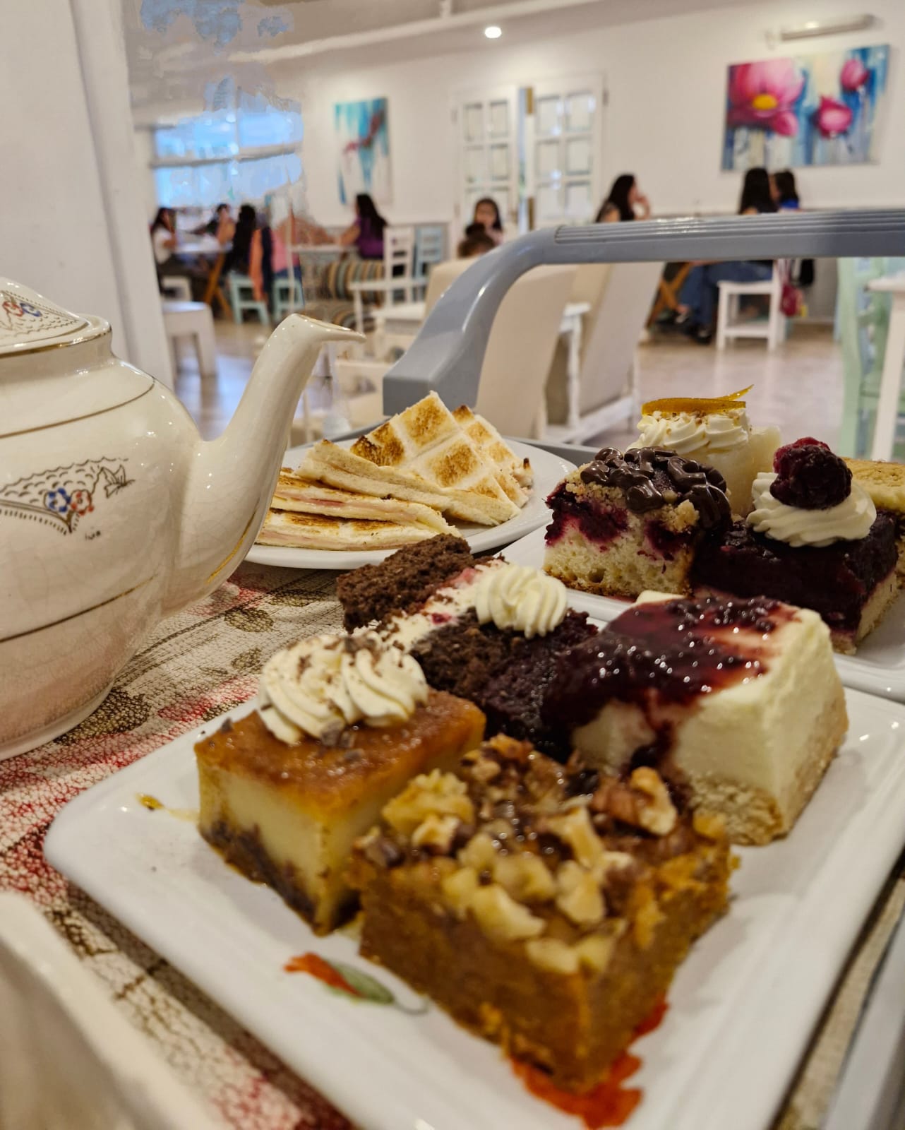 Carrito con platos de degustaciones de varias tortas junto a una tetera